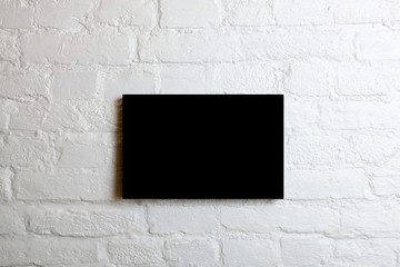 Black blank poster in a white brick wall. Template Mock up for your content