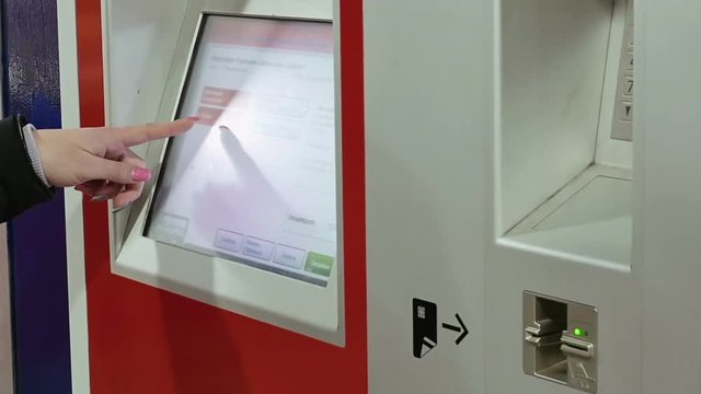 Ticket machine in metro subway underground tube is being used by young lady. Woman buys tickets at public transportation station self service ticket machine.