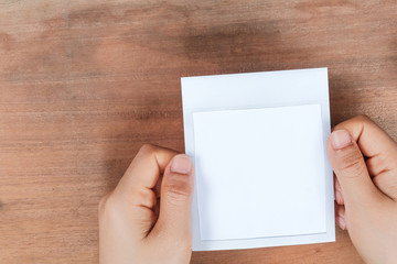 Obraz premium Hand holding a blank photo frame in front of wooden background.