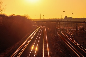 The setting sun reflecting off Burlington Northern Santa Fe and Metra railroad tracks in Aurora,...