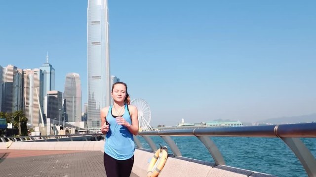 Slow motion. Young fitness woman runner running at Hong Kong city.