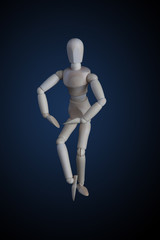 Wooden figurine crossing legs in elegant dance move on dark background