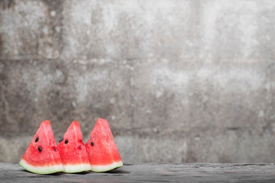 Fresh watermelon slice on wooden table with old brick wall background