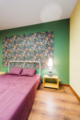 Interior bedroom with a large double bed with bedside tables, picture on the wall on a background of modern wallpaper