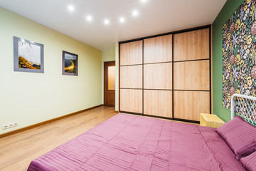 Interior bedroom with a large double bed with bedside tables, picture on the wall on a background of modern wallpaper