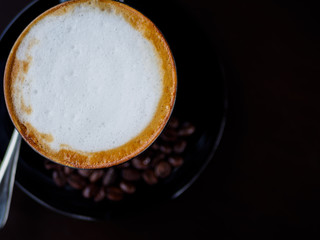 closeup cappuccino coffee on black cup with coffee bean on dark background