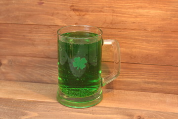 St Patrick's Day concept. Mug of green beer and a three-leaf clover against a wooden background