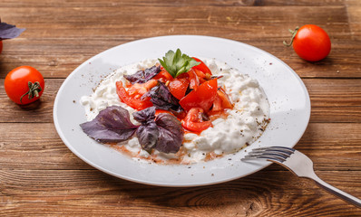 Salad with cottage cheese and tomatoes on wood table.