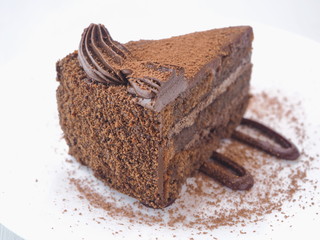 Food background. Piece of chocolate cake isolated on white. Slice of fresh brownie arranged on white plate.  Close-up image. Selective focus on the front.