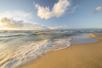 Baltic sea at beautiful sunrise,stony beach after storm