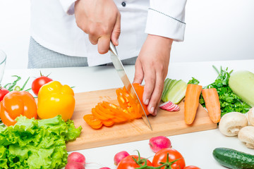 Chef cuts carefully sweet orange peppers for a vegetable salad