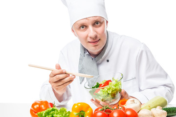 smiling chef peremshivaet vegetable salad with a wooden spoon on a white