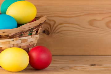 beautiful bright Easter eggs and a basket on the wooden background