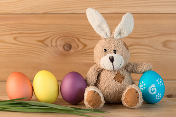 easter bunny and colored eggs in a row on a wooden background