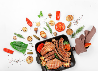 Cast iron grill pan with steak, sausages, grilled vegetables
