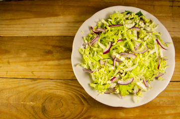 Salad with chinese cabbage and onion on wooden table
