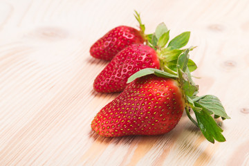 Three strawberries on a white board as background