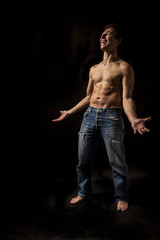 Fototapeta na wymiar Isolated shirtless caucasian man with jeans standing smiling with open arms. Black background