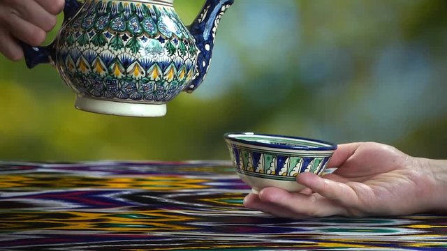 Young girl pouring tea into piala in asian cafe, Samarkand, Uzbekistan