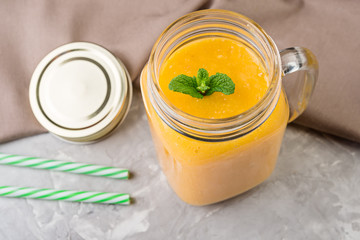 Fresh tropical smoothie in a glass with mango and orange