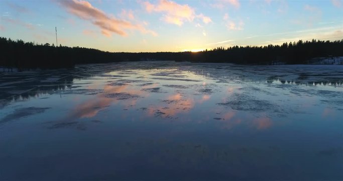 Sunset clouds mirroring on a lake, Cinema 4k aerial view of evening sky clouds mirroring on a icy lake, in siikaj&auml;rvi, of Nuuksio national park, in Finland