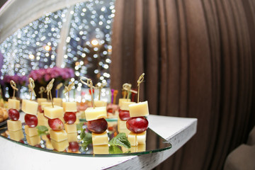 Appetizer of grape, pineapple cubes and cheese are on wooden skewers.