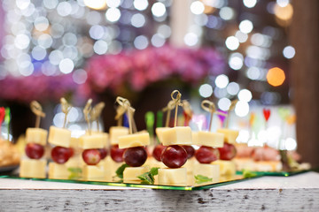 Appetizer of grape, pineapple cubes and cheese are on wooden skewers.