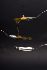 Honey pouring from spoon against a dark background