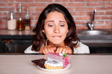 Woman on the diet craving to eat cake - obrazy, fototapety, plakaty