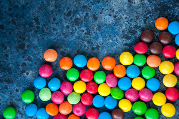Fototapeta na wymiar Colorful round candies scattered over blue background