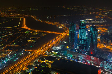 Panoramic aerial view on downtown of Dubai, UAE with modern high skyscrapers at night. Architecture of future with bright lights and roads. United Arab Emirates famous tourist destination