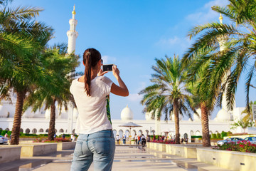 Young tourist woman shooting on mobile phone Sheikh Zayed great white mosque in Abu Dhabi, United...