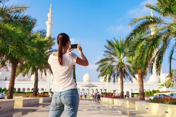 Zelfklevend Fotobehang Young tourist woman shooting on mobile phone Sheikh Zayed great white mosque in Abu Dhabi, United Arab Emirates, Persian gulf. UAE is famous tourism destination © oleg_p_100