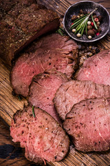 Roast beef on cutting board with salt and pepper. Top view.