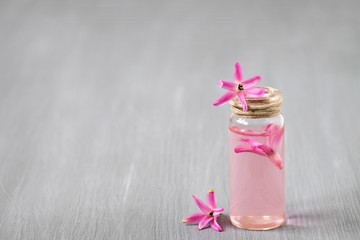 Essential oil glass bottle, pink hyacinth, wooden background