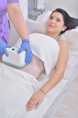 Pretty young woman getting cryolipolyse fat treatment in professional cosmetic cabinet