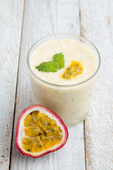 Smoothies passion fruit, milk in a glass on a white wooden background.