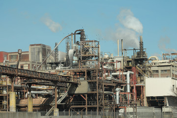 Obraz premium A large industrial building with smoke coming out of the stacks.