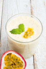 Smoothies passion fruit, milk in a glass on a light background closeup.