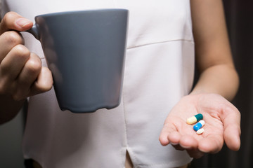 Woman hands with pills and Mug of water