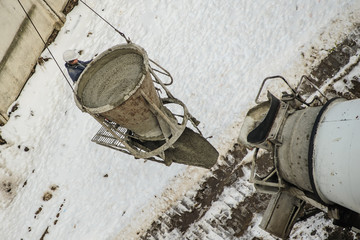 Concrete mixer truck pouring liquid concrete into the tower crane bucket