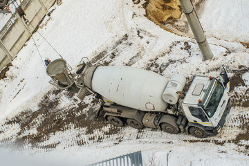 Concrete mixer truck pouring liquid concrete into the tower crane bucket