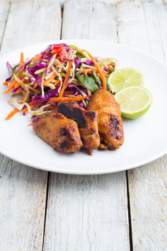 Wings Grill, Asian salad, lime on a white plate on a white table.
