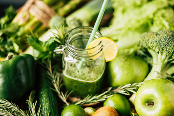 Freshly blended green fruit smoothie in glass jar with straw.