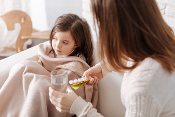Loving mother giving pills to her ill daughter