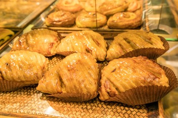 Small round apple pie displayed on wooden tray at bakery shop