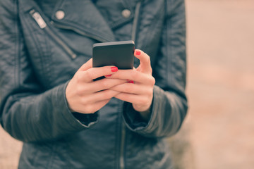 Detail of a girl holding a cellphone outdoors.