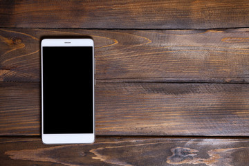 White mobile phone on a wooden background