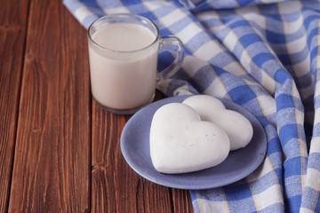 ginger biscuits in the shape of heart on a saucer and a cup of hot chocolate on a wooden table, rustic style