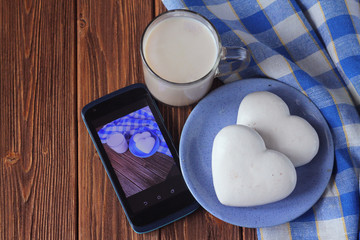  cup of cocoa, ginger biscuits in the shape of a heart and a smartphone on a wooden table